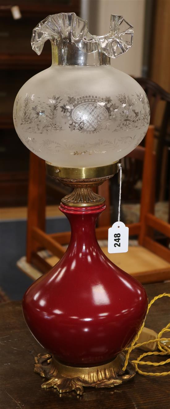 An oxblood red 19th century converted oil lamp and shade